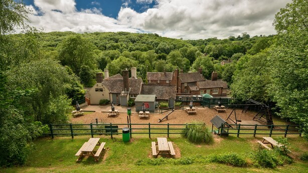 Un village traditionnel avec des bâtiments en pierre, des tables de pique-nique et une aire de jeux.