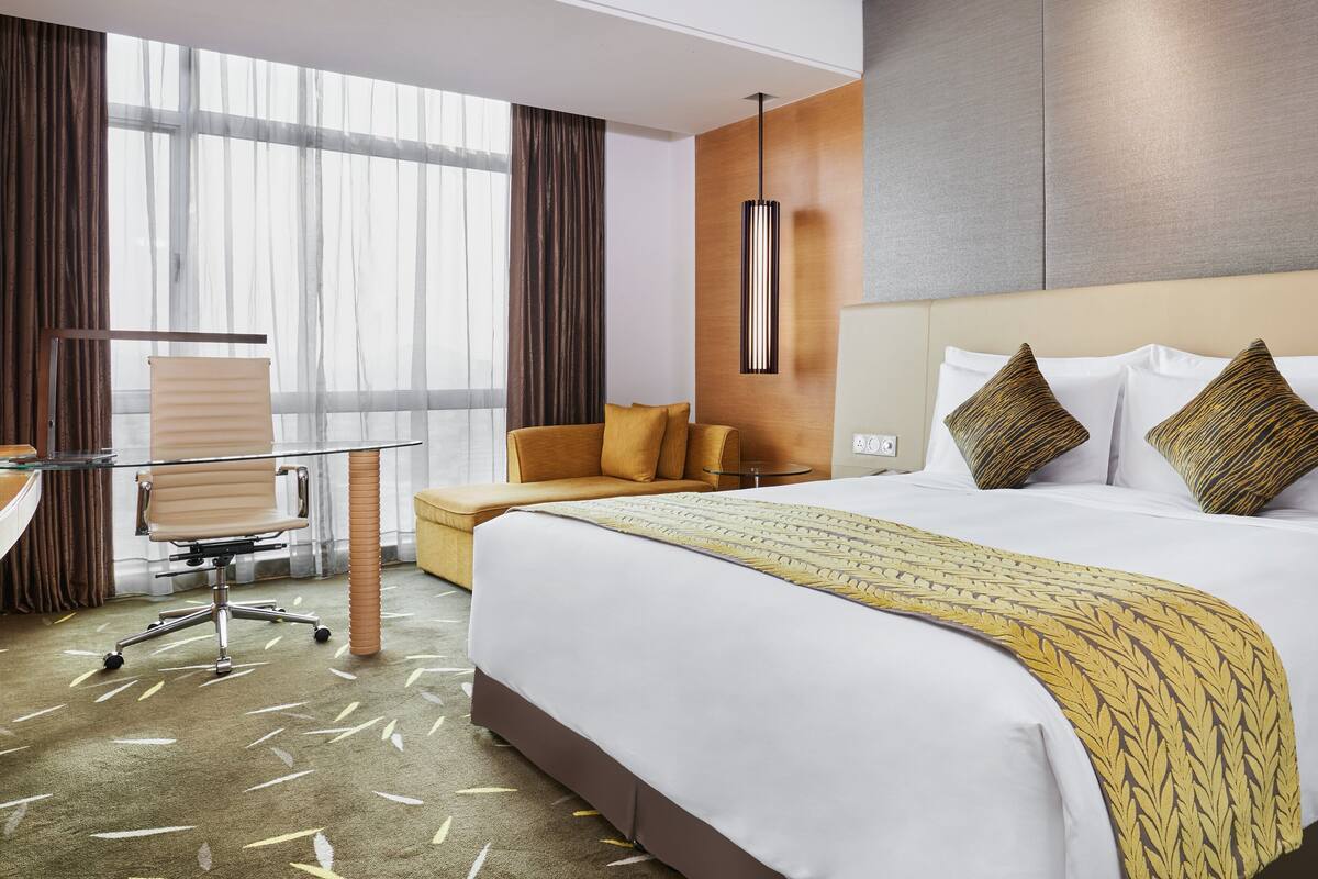 Une chambre d’hôtel avec un grand lit, un canapé, un bureau et une chaise.