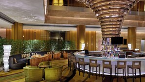 A modern lobby with a central bar, seating areas, and a decorative ceiling feature.