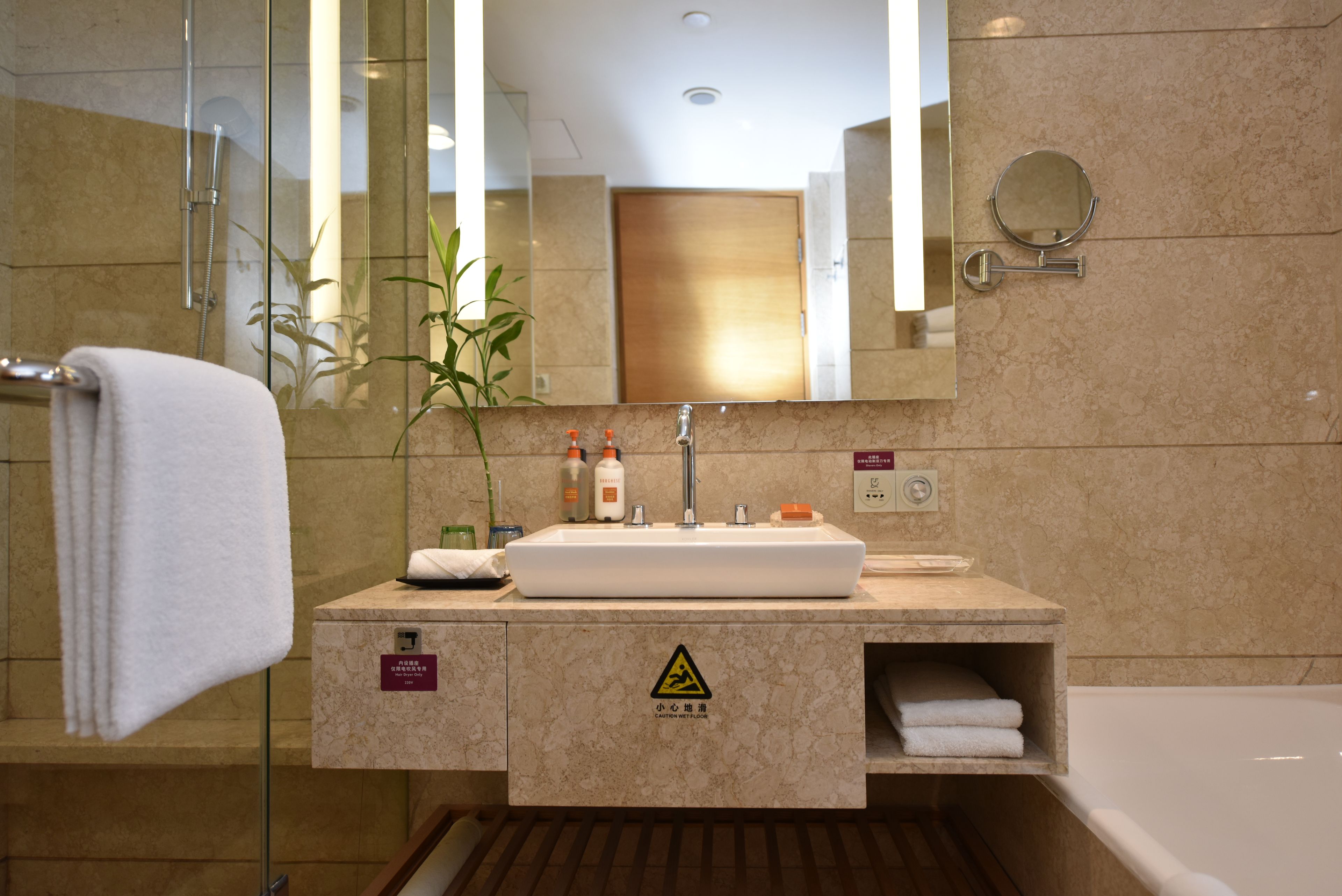 Un baño moderno con cabina de ducha de vidrio, un lavabo blanco y un espejo grande.