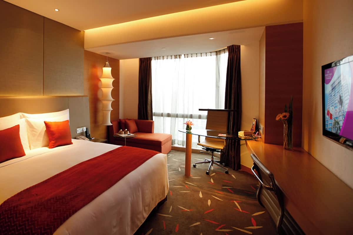 Une chambre d’hôtel avec un grand lit, un bureau, une chaise et un téléviseur.
