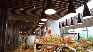 A buffet area with a variety of food items and a service staff member.