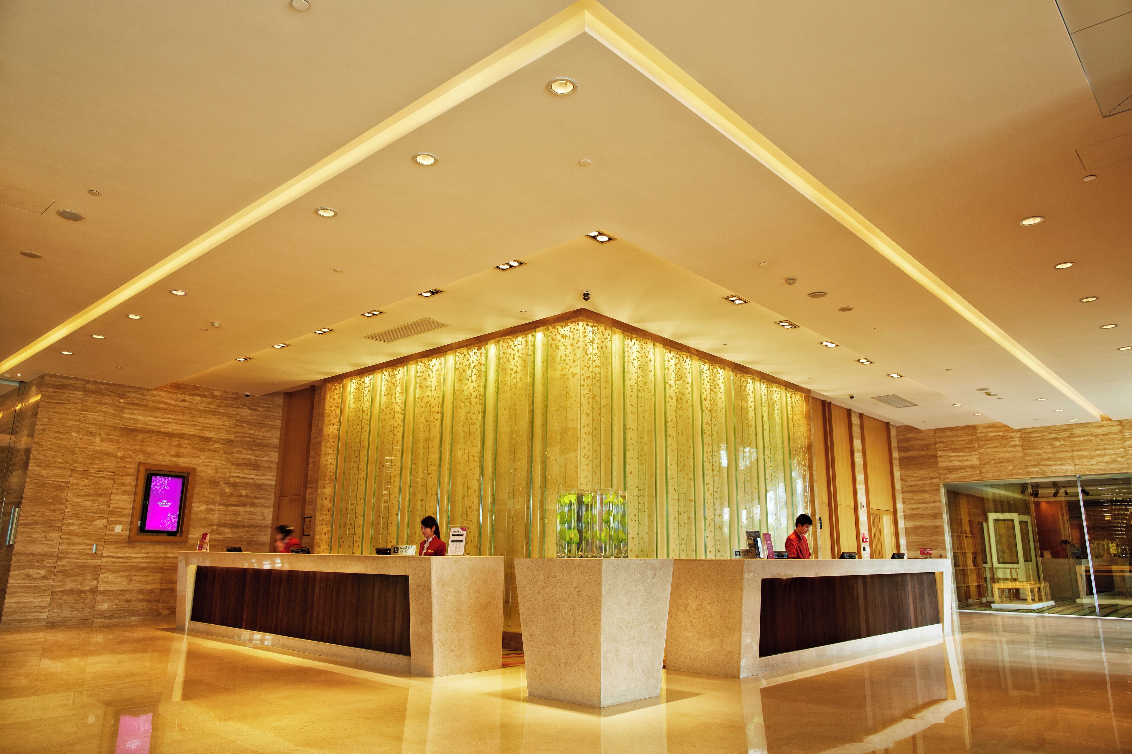 A hotel reception area with a modern design, featuring a reception desk, a large decorative curtain, and a polished floor.