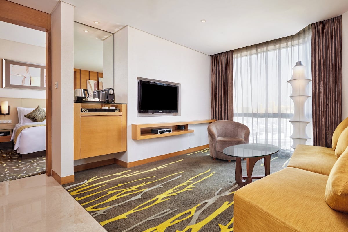 Une chambre d’hôtel équipée d’un lit, d’un canapé, d’une télévision, d’une machine à café et d’une fenêtre avec des rideaux.