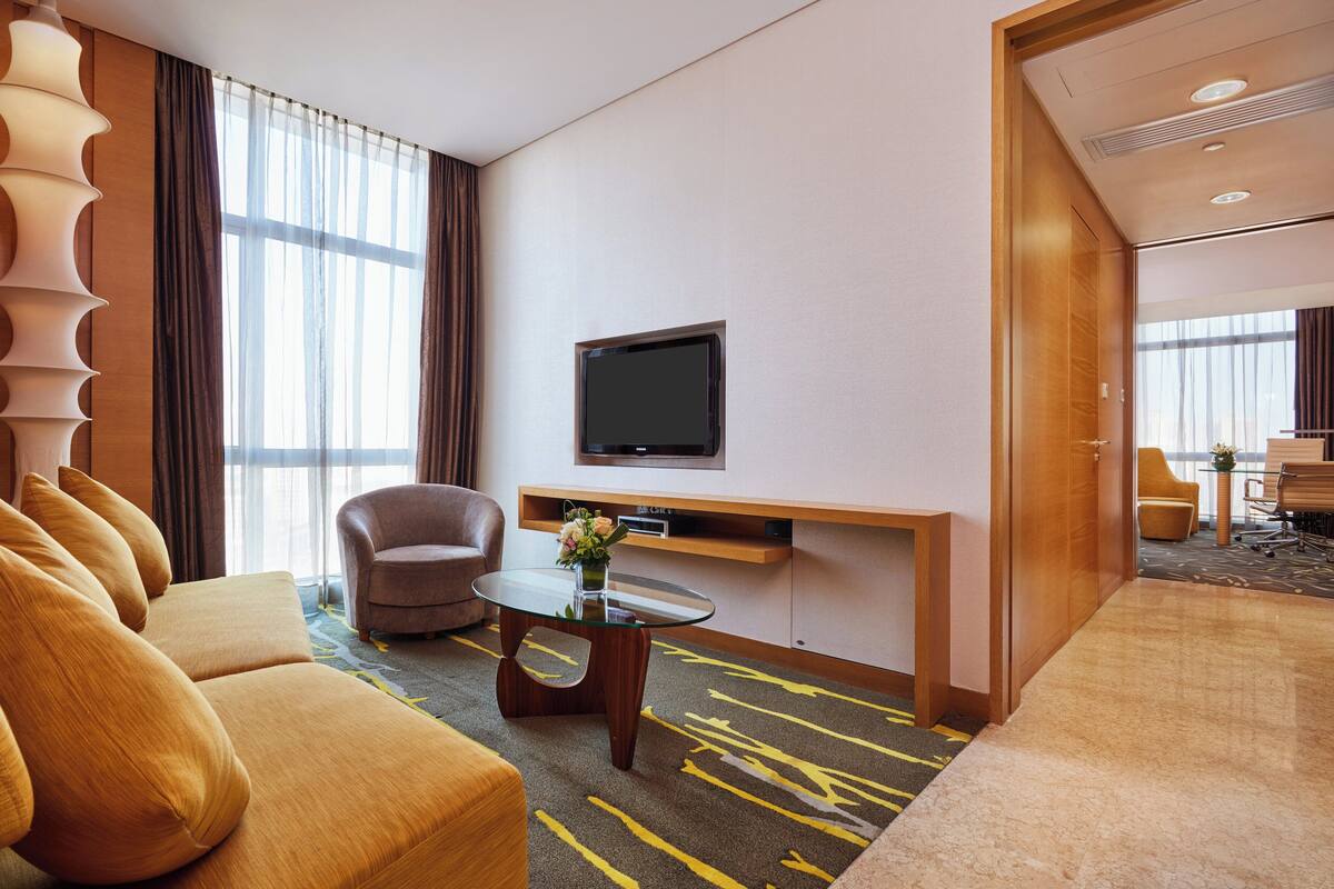 Une chambre d’hôtel avec un canapé, un fauteuil et une table basse en verre.