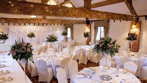 A banquet hall with round tables set for a formal event, featuring white tablecloths, chairs with white covers, and floral centerpieces. - Slaters Country Inn (Newcastle-Under-Lyme)