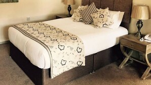 A bedroom with a bed, two bedside tables, and a wooden ceiling structure. - Slaters Country Inn (Newcastle-Under-Lyme)