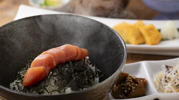 A bowl of sushi with a piece of salmon on top of rice and seaweed.