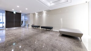 Un vestíbulo amplio con piso de mármol pulido, un banco moderno y un tragaluz.