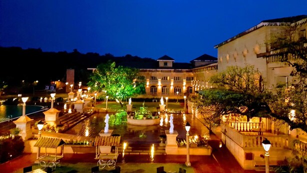 Un patio con una fuente, una zona de estar cubierta y un edificio con varios balcones.