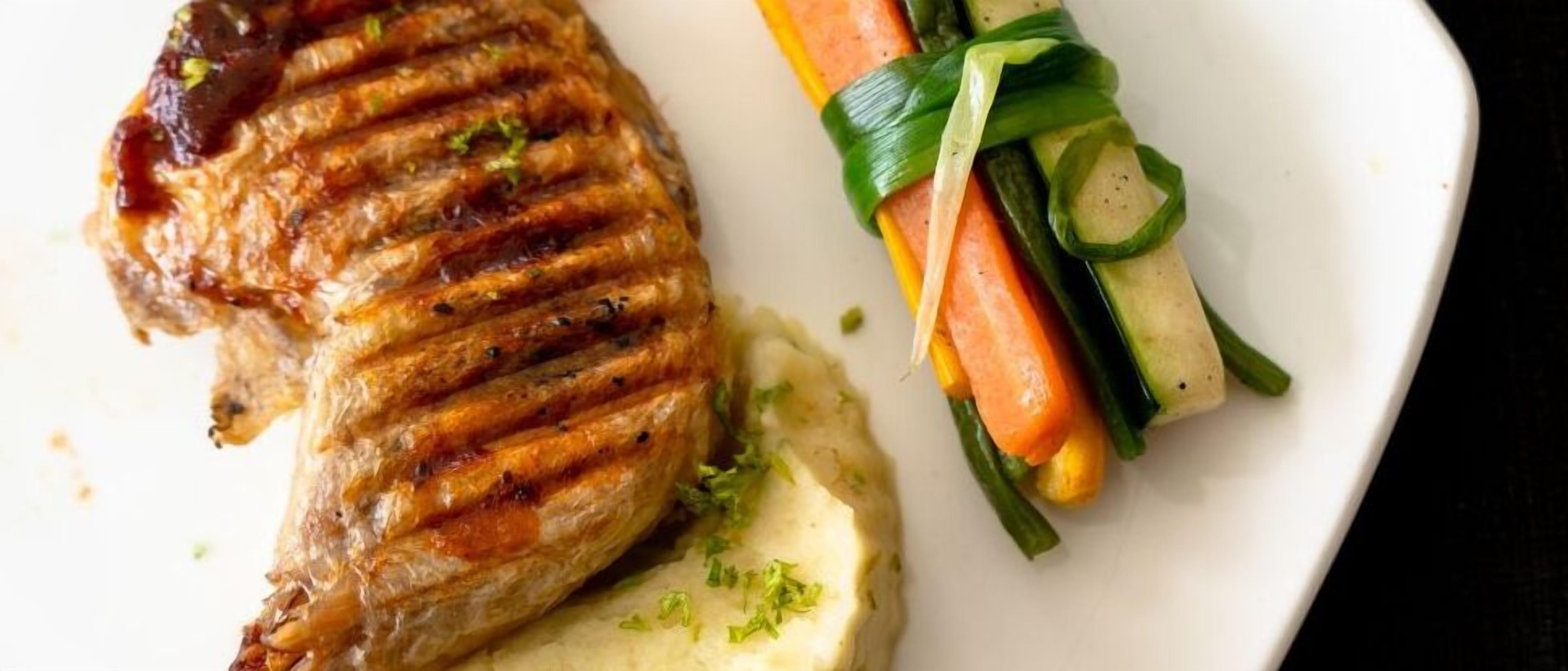 Um prato com carne grelhada, purê de batata e legumes.