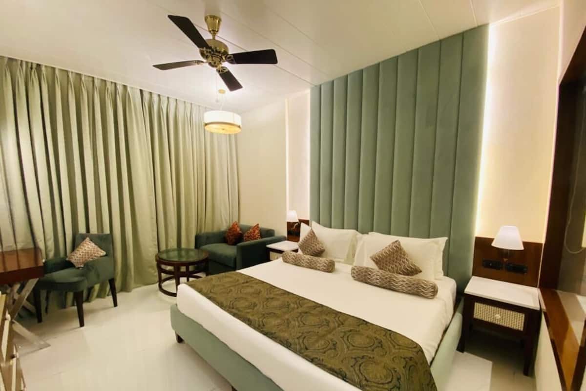 Habitación de hotel con una cama grande, ventilador de techo, escritorio, silla y una mesita.