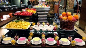 Un bufé con diversas frutas, postres y bebidas.