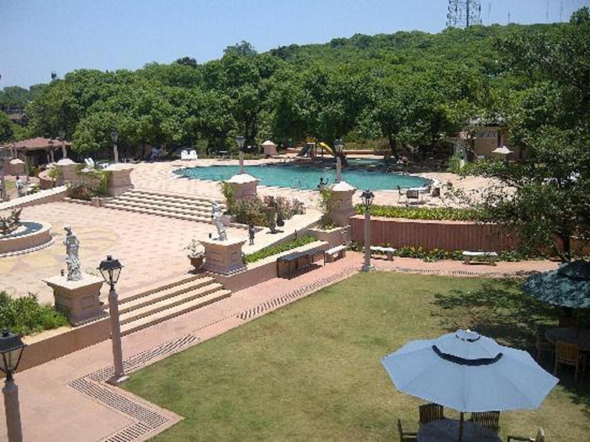 A landscaped area with a pool, steps leading to a gazebo, and a statue.