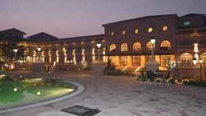 Un edificio grande con múltiples ventanales arqueados y un patio central con piscina.