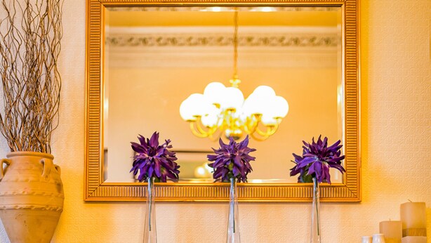 A fireplace with a mantel, a mirror above it, and decorative vases with purple flowers. - Strathallan Guest House (Edinburgh)