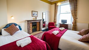 A hotel room with two beds, a fireplace, a television, and a window with curtains. - Strathallan Guest House (Edinburgh)