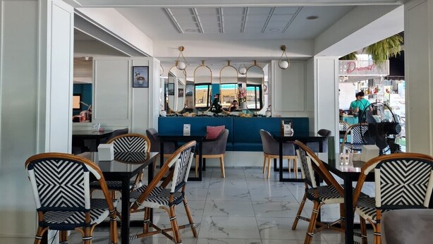 A modern restaurant with a central seating area, a bar, and a view of the street. - Opal House Hotel & Restaurant (Pattaya)