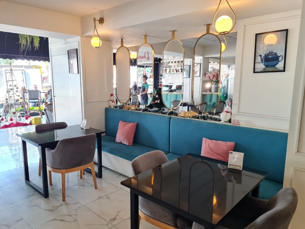 Un interior moderno con un sofá azul aguamarina, una mesa de comedor negra y un espejo.