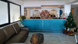 A reception area with a blue counter, a sofa, a coffee table, and a Christmas tree. - Opal House Hotel & Restaurant (Pattaya)