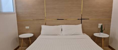 Habitación de hotel con una cama grande, dos mesitas de noche, una lámpara de pared y una pequeña planta en maceta.