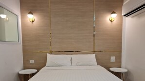 A hotel room with a large bed, two bedside tables, a wooden headboard, and wall-mounted lights. - Opal House Hotel & Restaurant (Pattaya)
