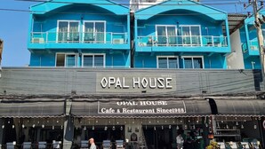 A building with a sign reading "OPAL HOUSE Cafe & Restaurant Since 1988" and balconies with railings. - Opal House Hotel & Restaurant (Pattaya)