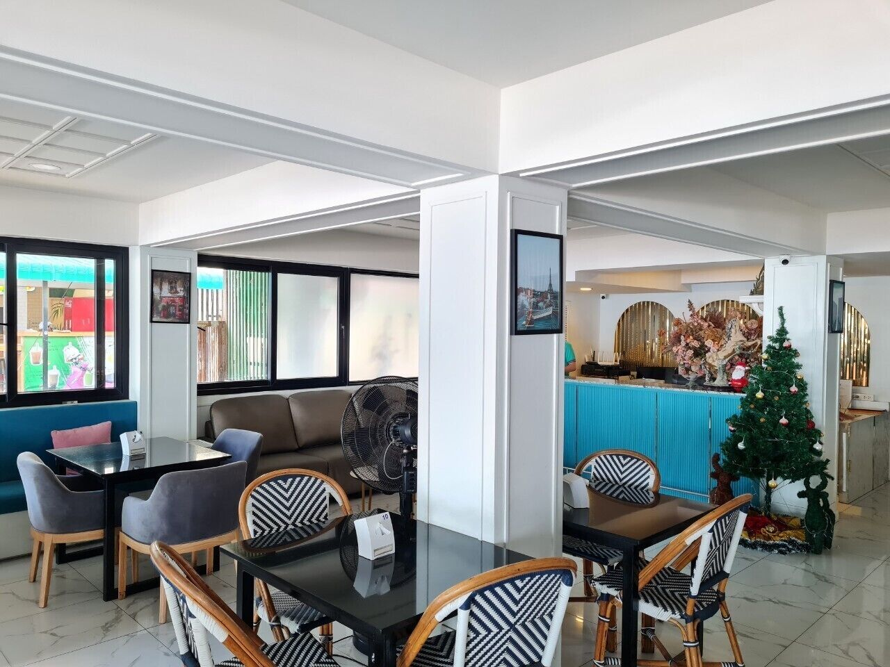 A modern dining area with a glass table, cushioned chairs, and a small Christmas tree.
