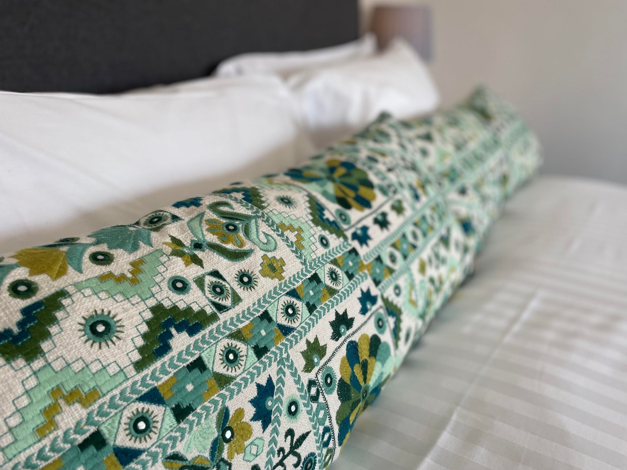 Een bed met een gestreept kussen en een effen wit kussen.