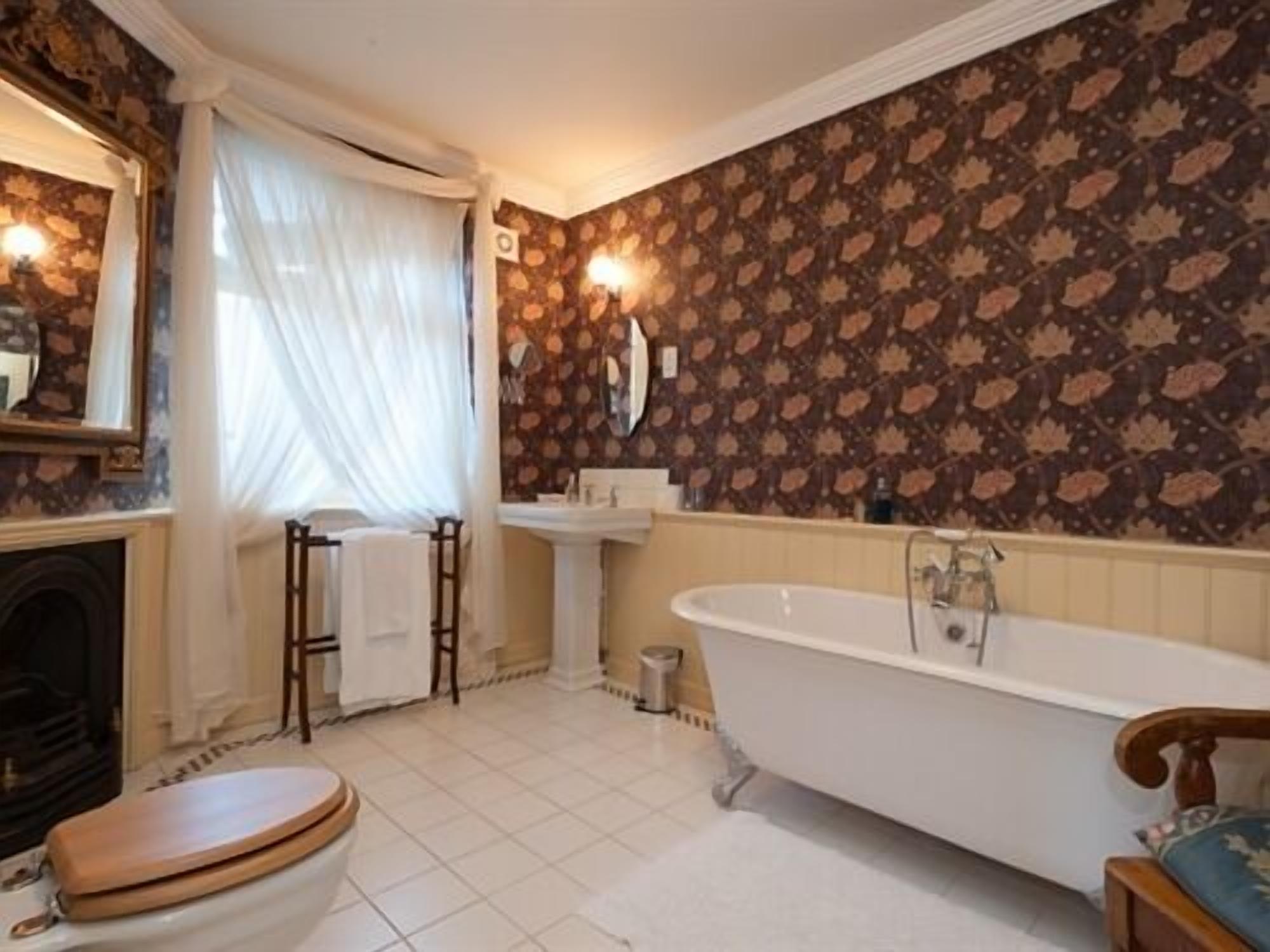 Une salle de bain avec une baignoire sur pieds, des toilettes, un lavabo et un miroir.