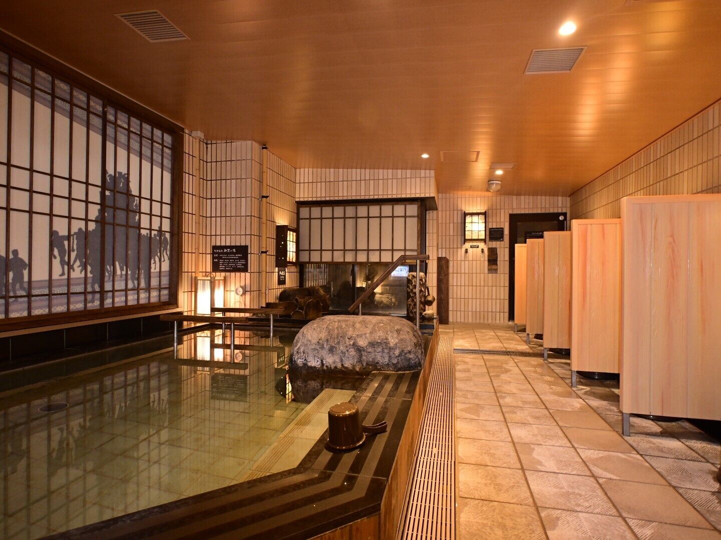Ein traditionelles japanisches Bad mit Tatami-Boden, einem Steinbecken und Holztüren.