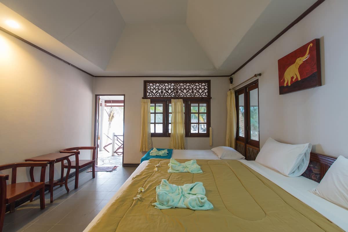 A hotel room with a bed, a desk, and a chair. There is a window with curtains and a decorative screen.