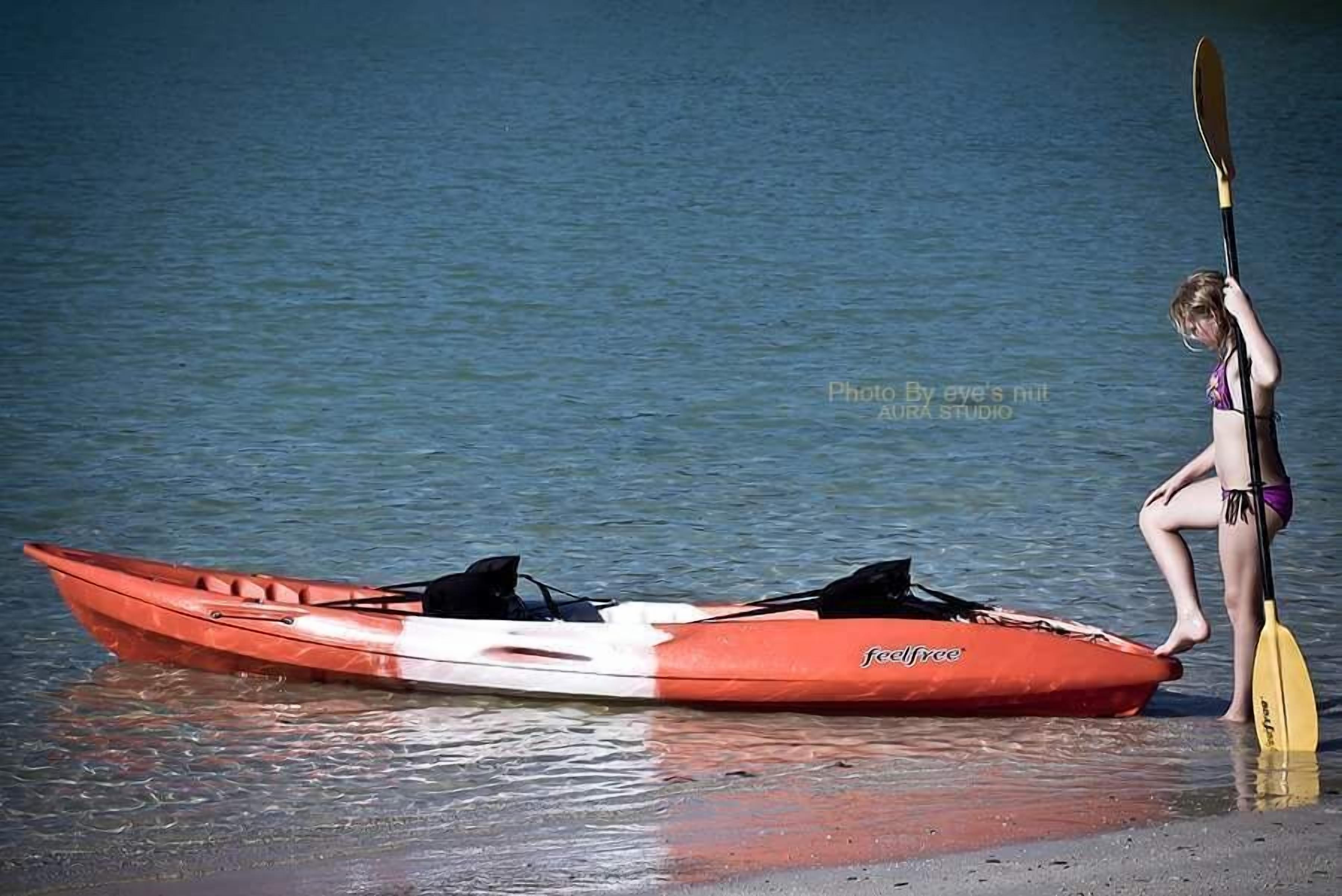 A kayak on a beach with a paddle.