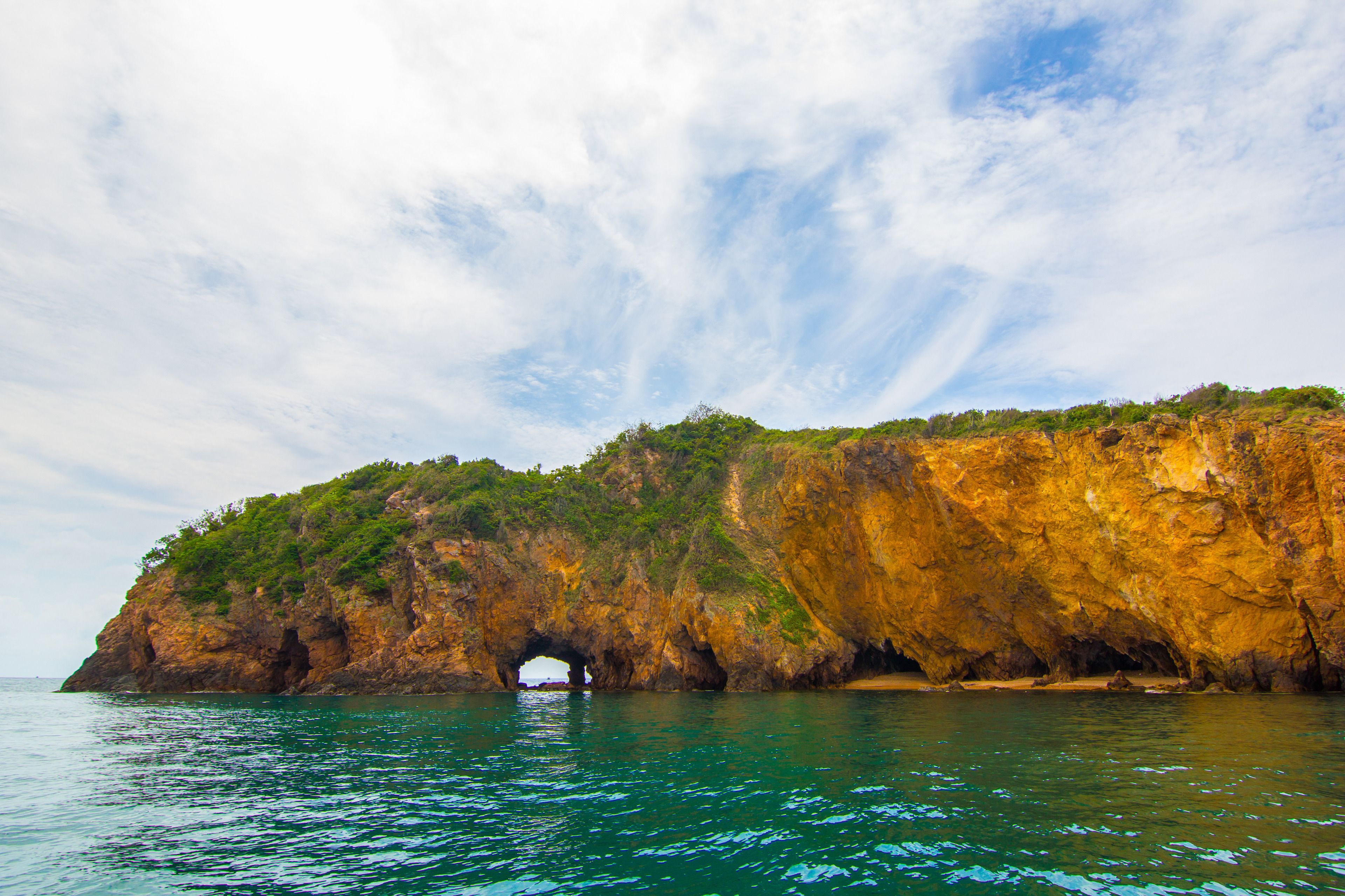 A coastal landscape with a prominent rock formation featuring a natural archway.