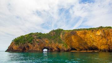 A coastal landscape with a prominent rock formation featuring a natural archway.