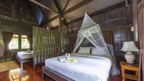 A bedroom with a large bed, a bedside table, a lamp, and a window with curtains. - Koh Talu Island Resort (Bang Saphan Noi)