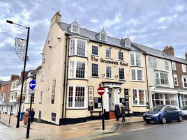 The Brunswick Hotel with a traditional facade, multiple windows, and a sign indicating rooms for rent.