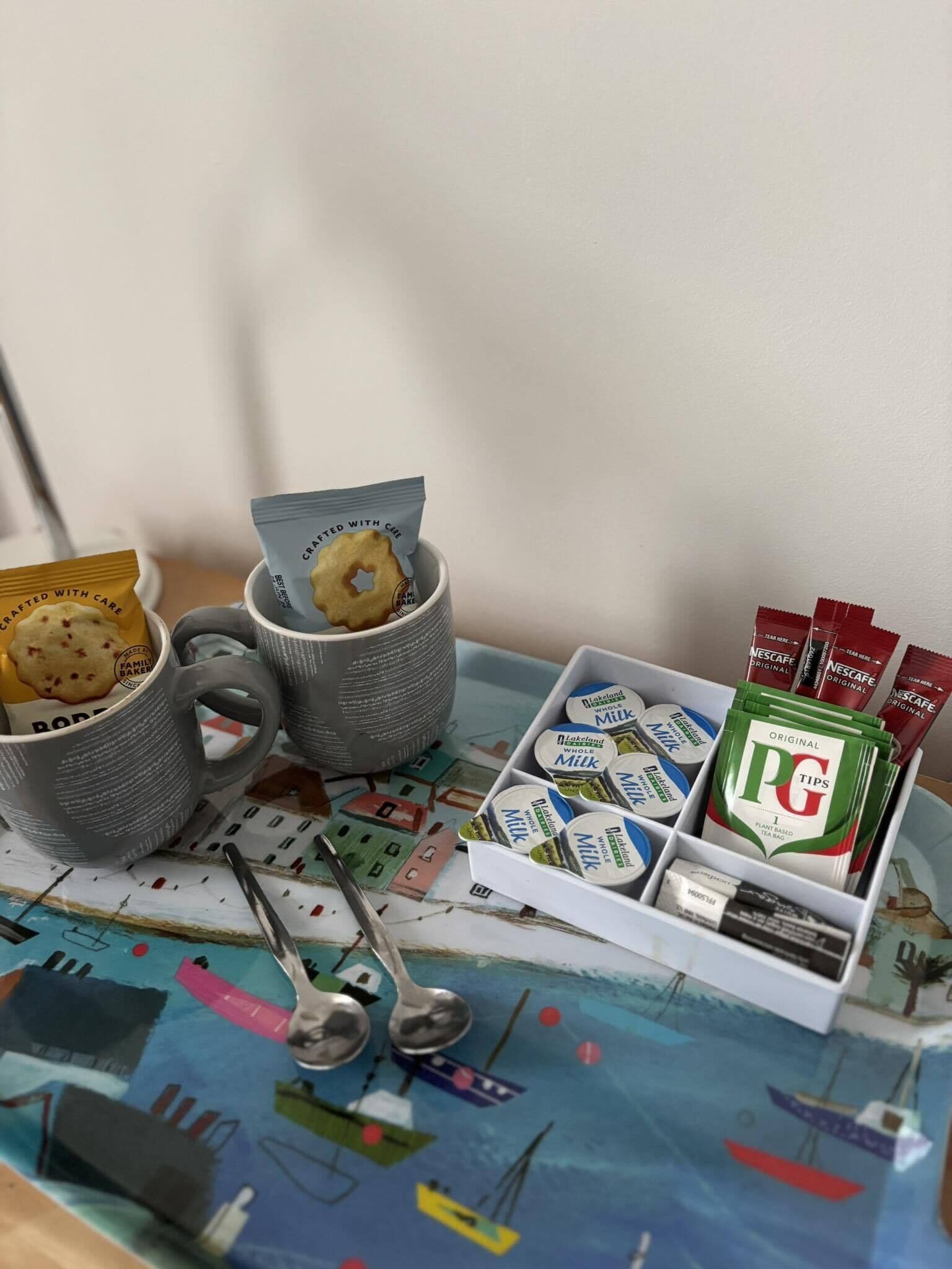 A table with mugs, cookies, and tea bags.