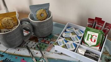 A table with mugs, cookies, and tea bags.
