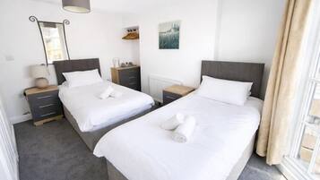 Une chambre d’hôtel avec deux lits, une commode, un miroir et une fenêtre avec des rideaux.