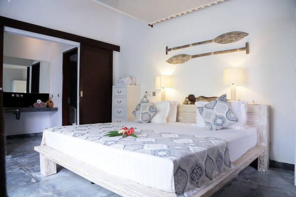 A bedroom with a bed, bedside lamps, a mirror, and a wooden headboard.