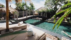 A pool area with lounge chairs and a thatched-roof structure.