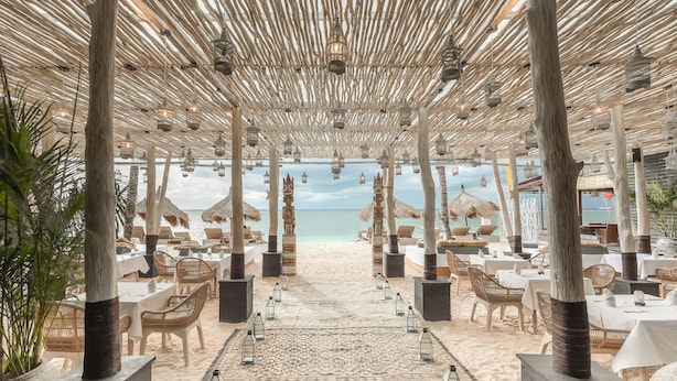 An outdoor dining area with tables and chairs, a patterned rug, and lanterns.