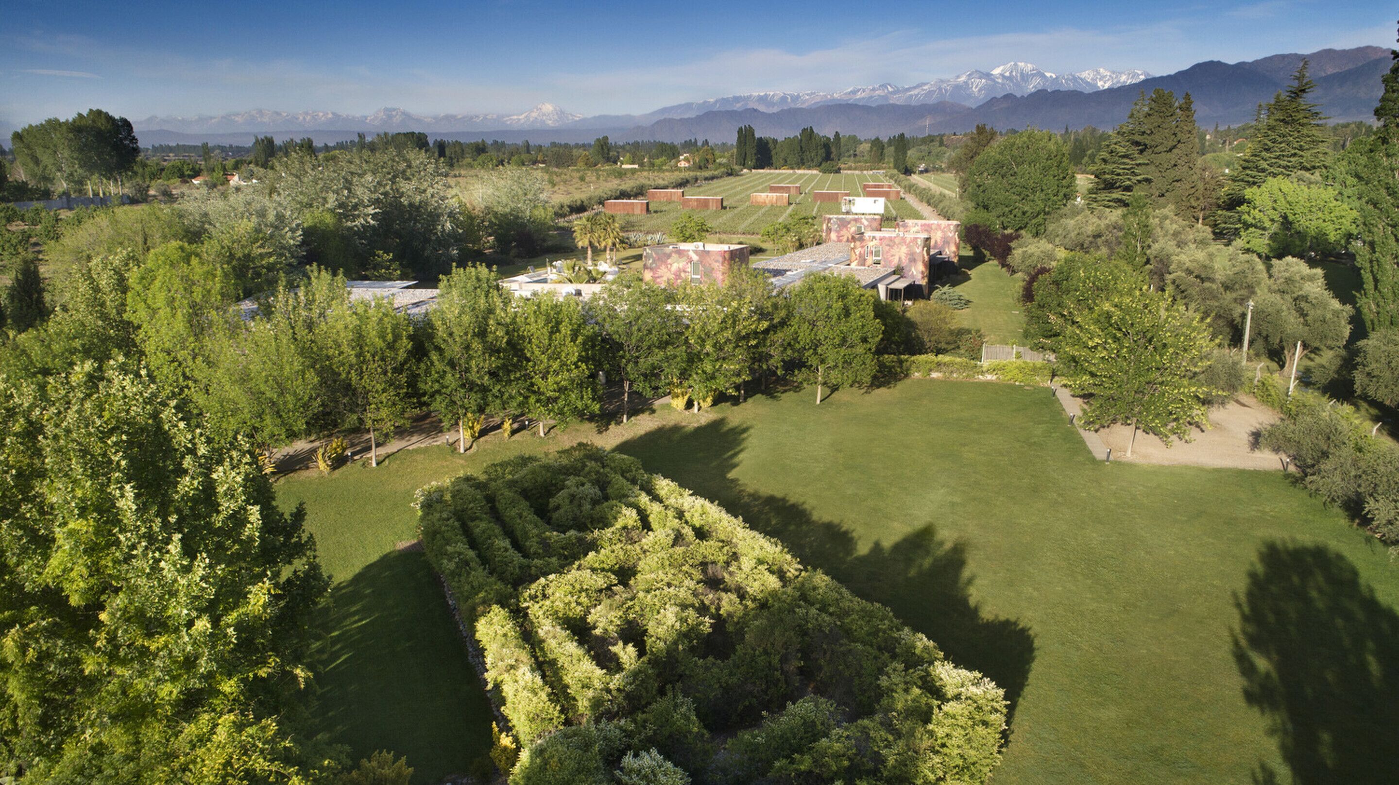 Un campo de golf con un gran césped, árboles y edificios al fondo.