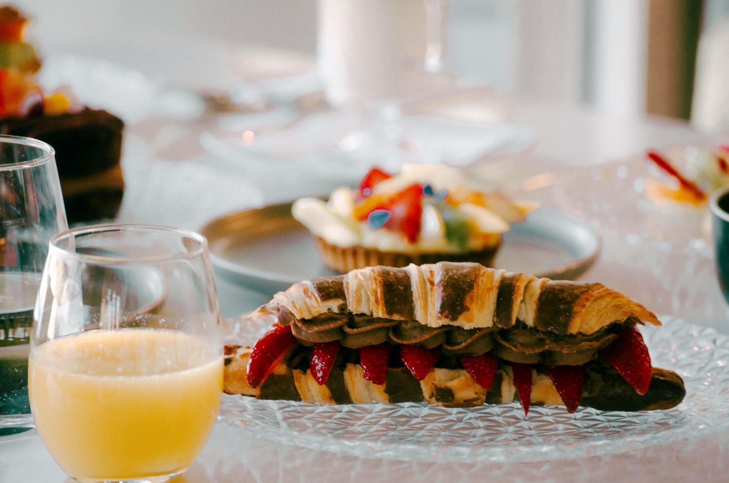 A dessert plate with a layered pastry and a glass of orange juice on a table.