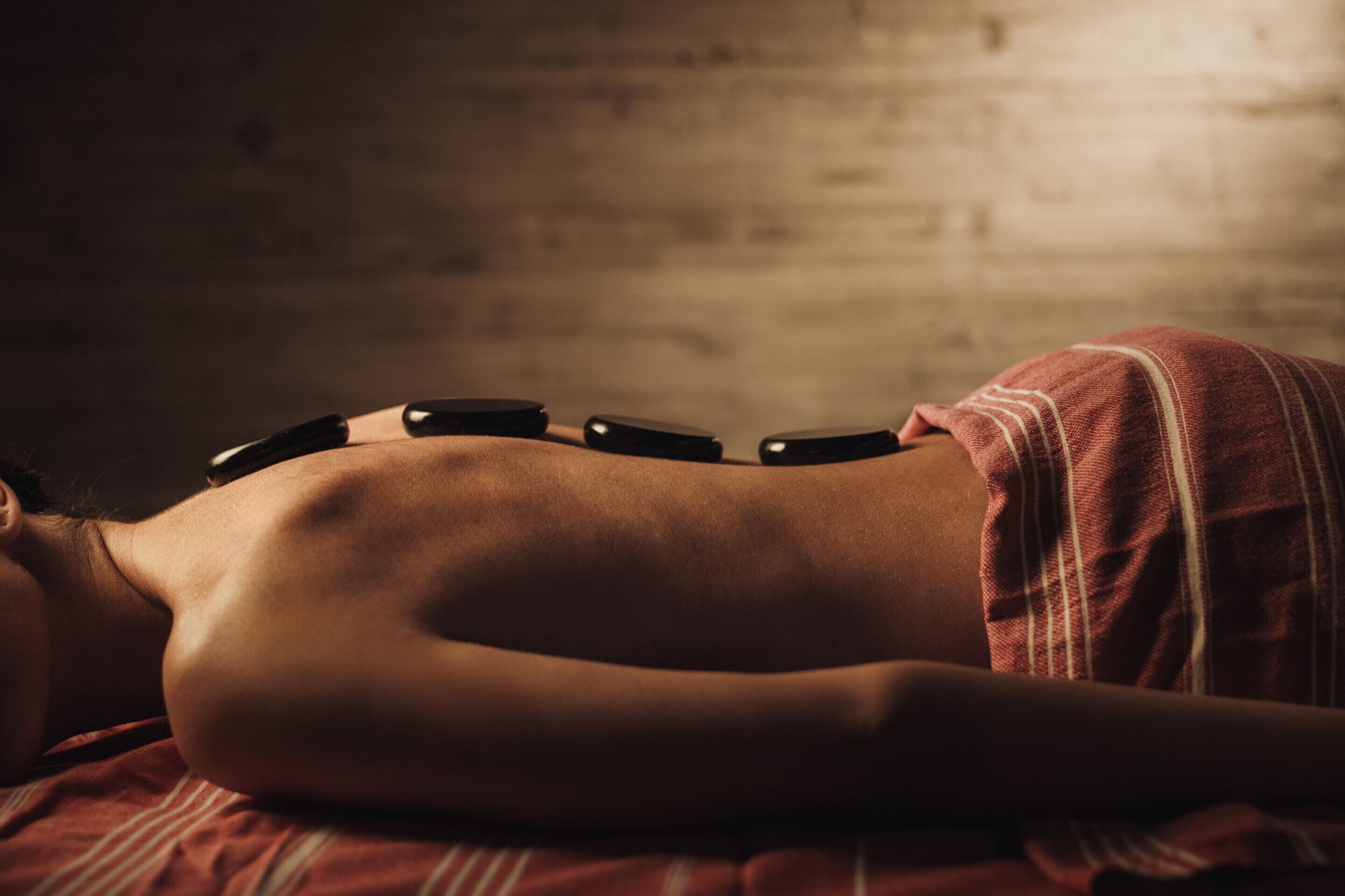 Una persona sdraiata su un letto con una coperta, avvolta in un asciugamano rosso.