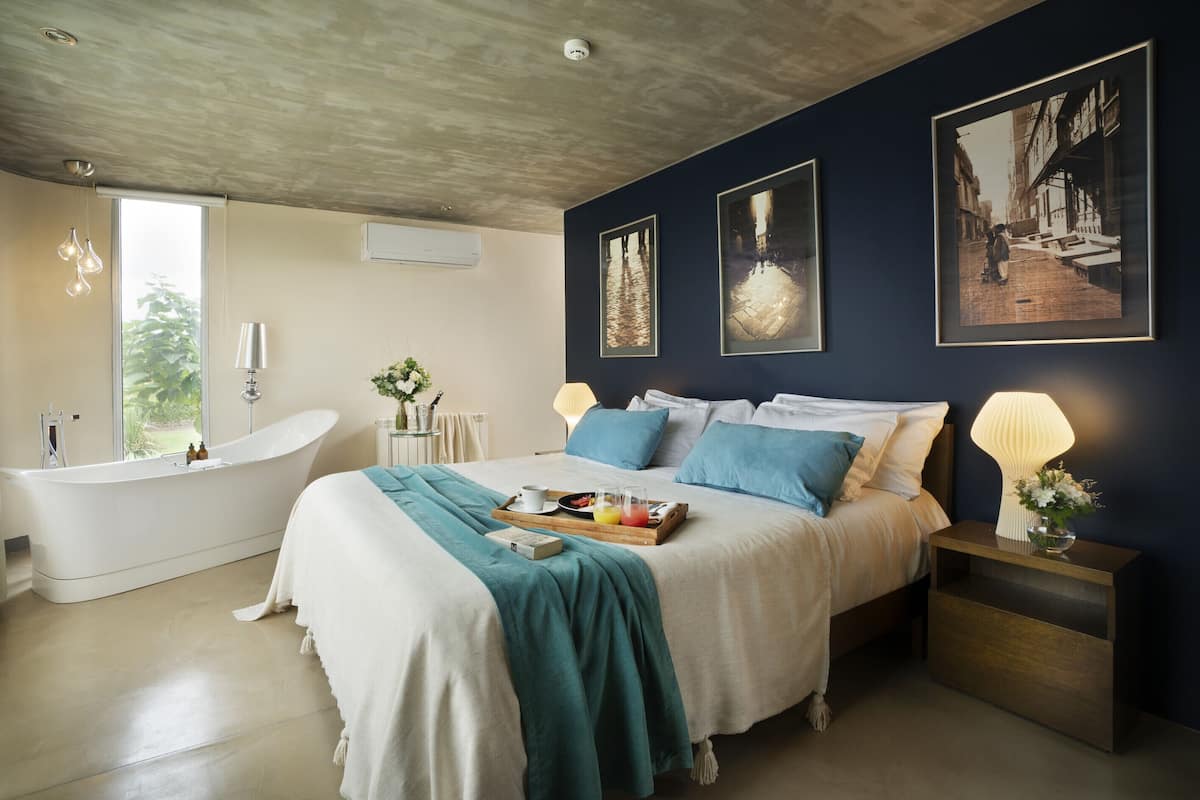 Ein Schlafzimmer mit einem großen Bett, einer Badewanne und Kunstwerken an den Wänden.