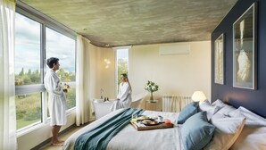 A hotel room with a large bed, a bathtub, and a view of the outdoors. - Entre Cielos Wine & Wellness Hotel (Luján de Cuyo)