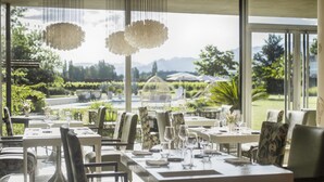 Comedor con mesas dispuestas para el servicio, sillas e lámparas colgantes.