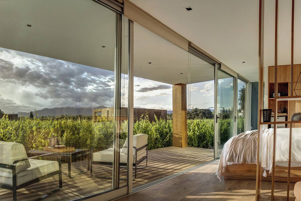 Ein modernes Schlafzimmer mit einem großen Glasfenster, das auf eine Terrasse im Freien führt.